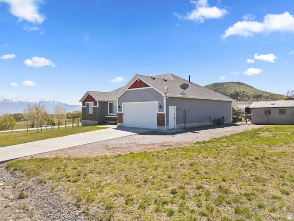 View of front facade featuring a mountain view, a front yard, driveway, and a garage