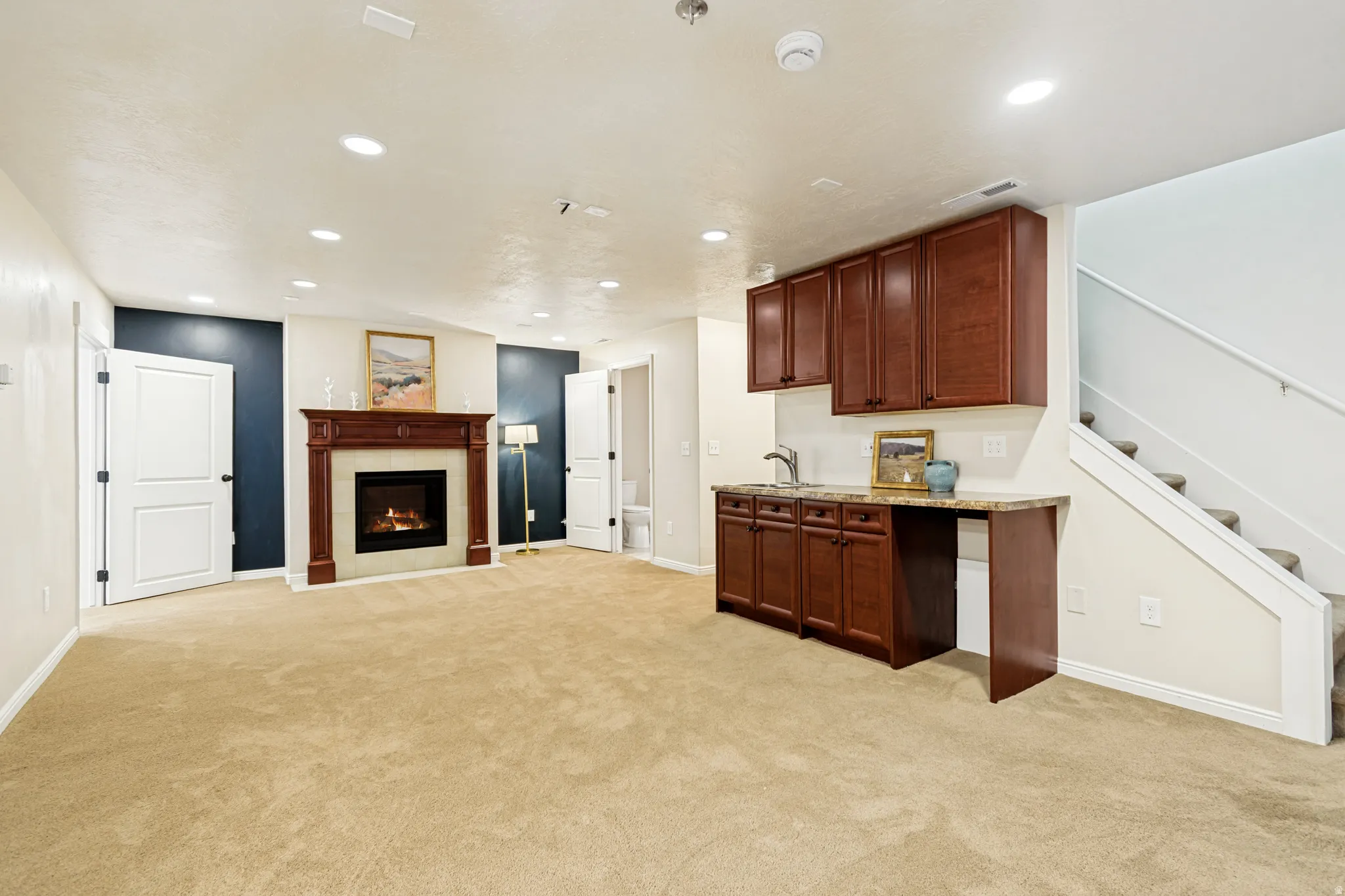 Kitchen featuring open floor plan, light carpet, recessed lighting, a fireplace, and light stone counters
