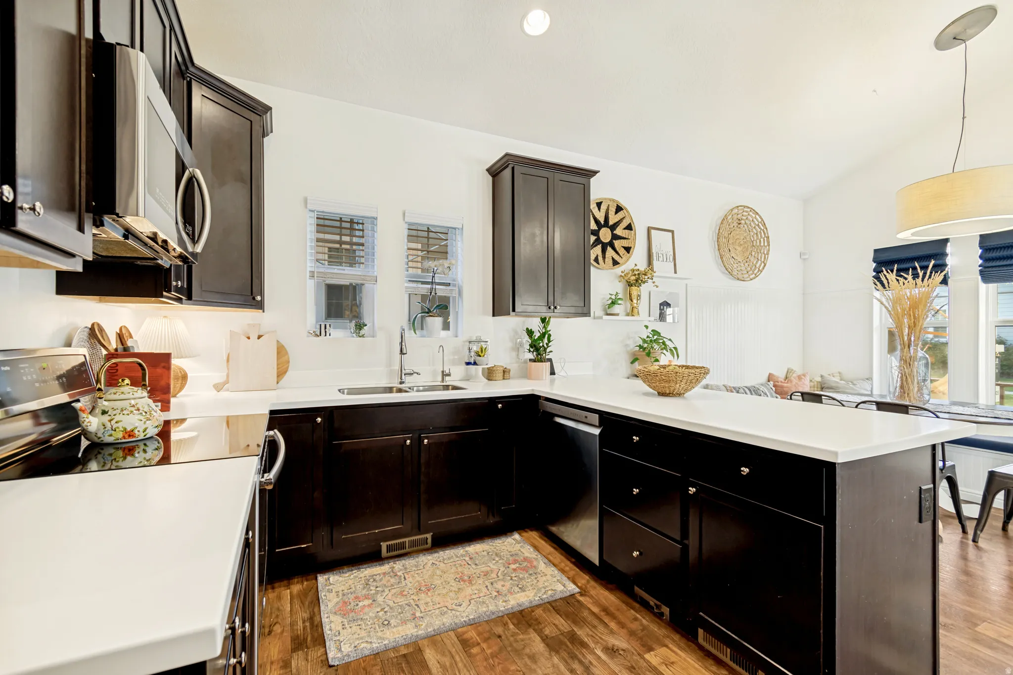 Kitchen featuring a peninsula, stainless steel appliances, light countertops, vaulted ceiling, and dark wood finished floors