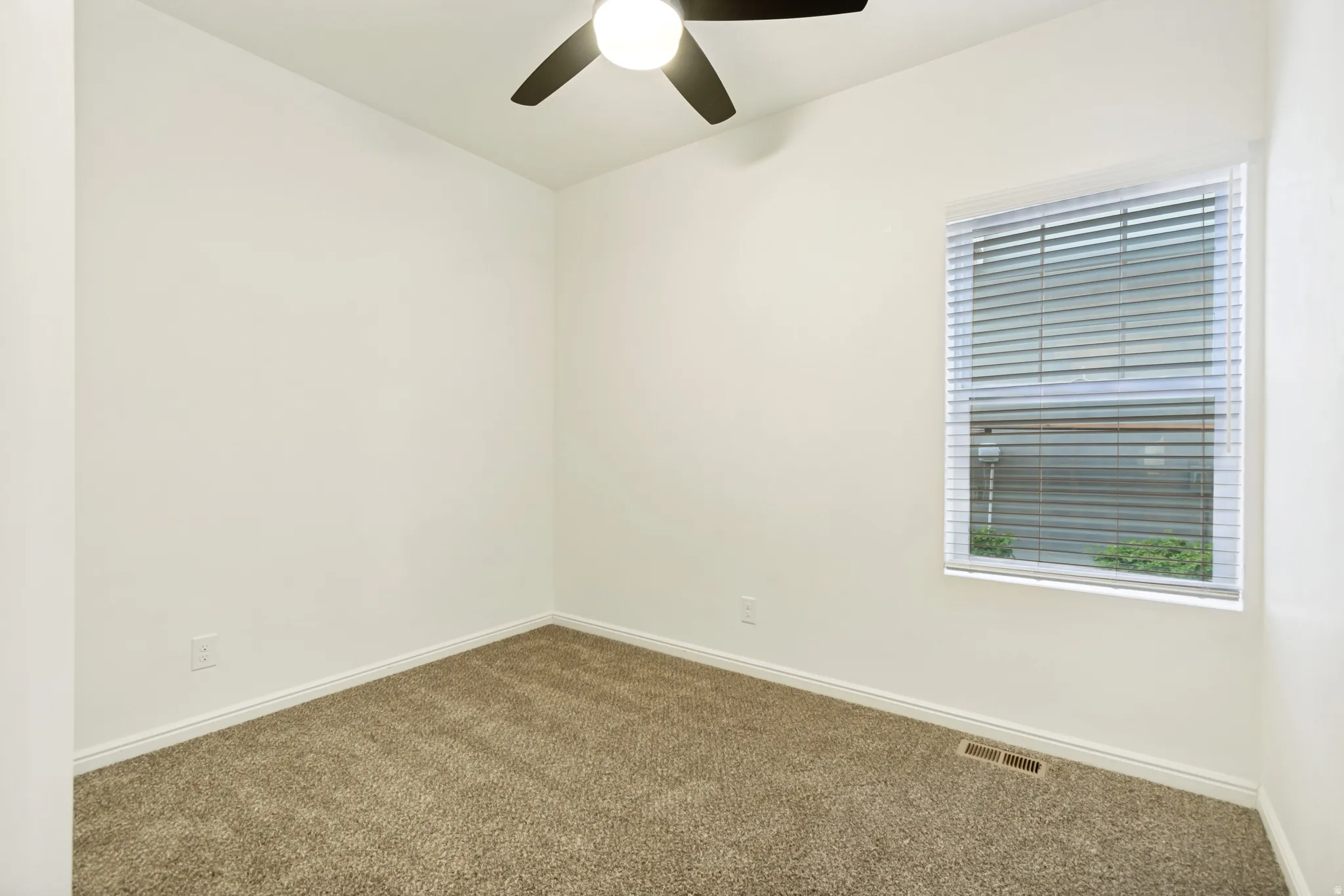 Empty room featuring dark carpet and a ceiling fan