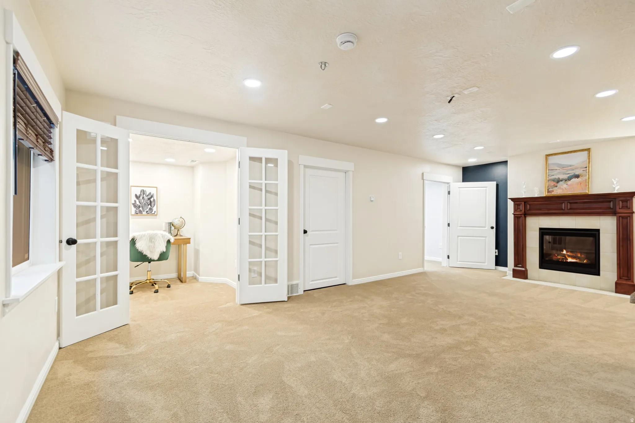 Unfurnished living room featuring french doors, light colored carpet, a fireplace, and recessed lighting