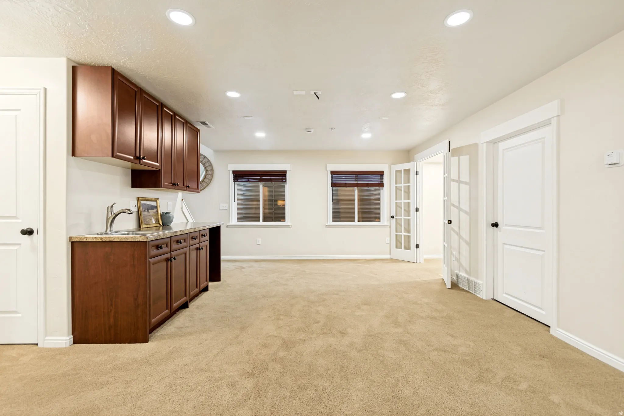 Kitchen with light carpet, recessed lighting, light stone counters, and dark wood finish cabinets