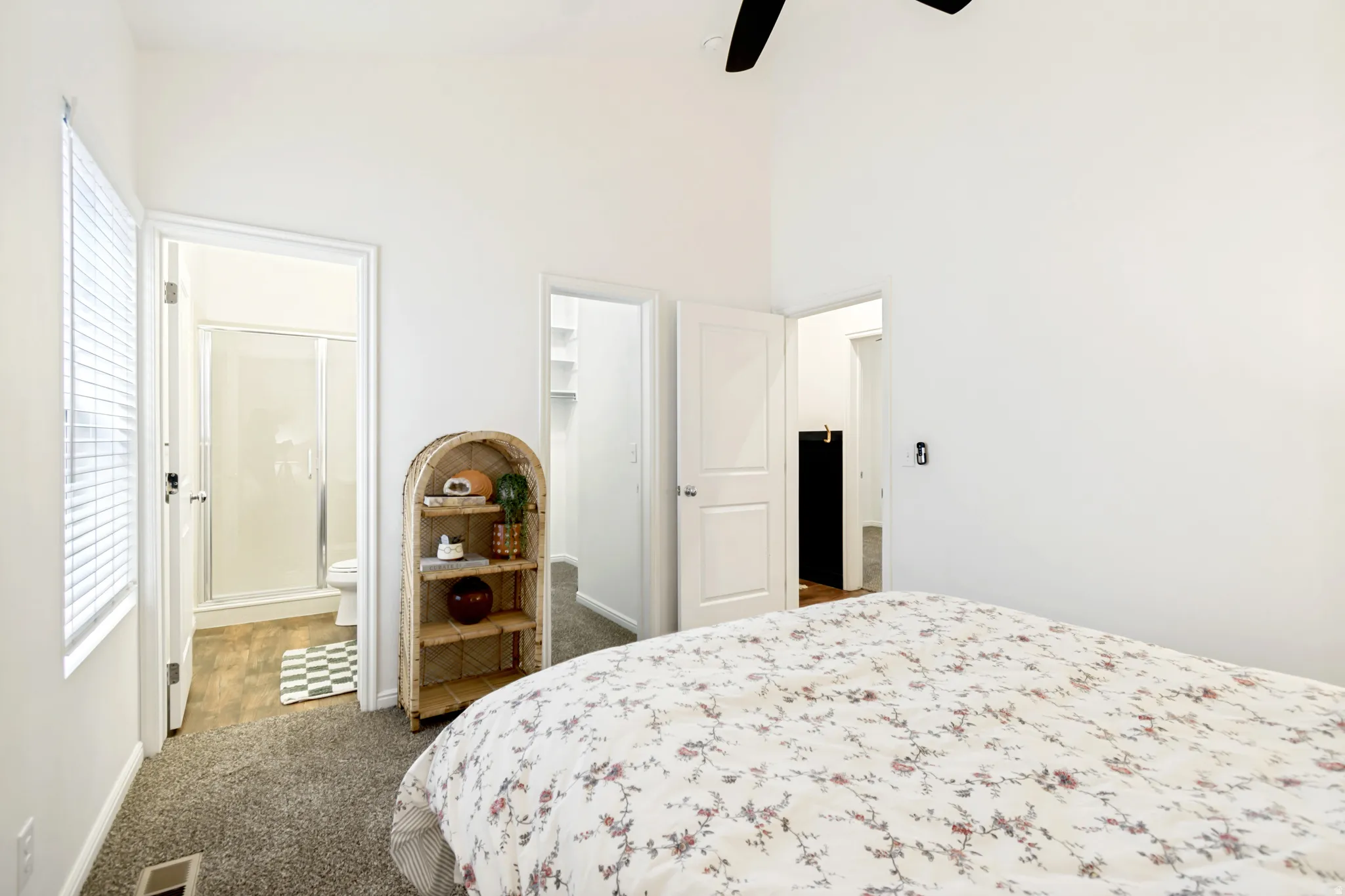 Bedroom with a walk in closet, carpet, ceiling fan, a high ceiling, and ensuite bath