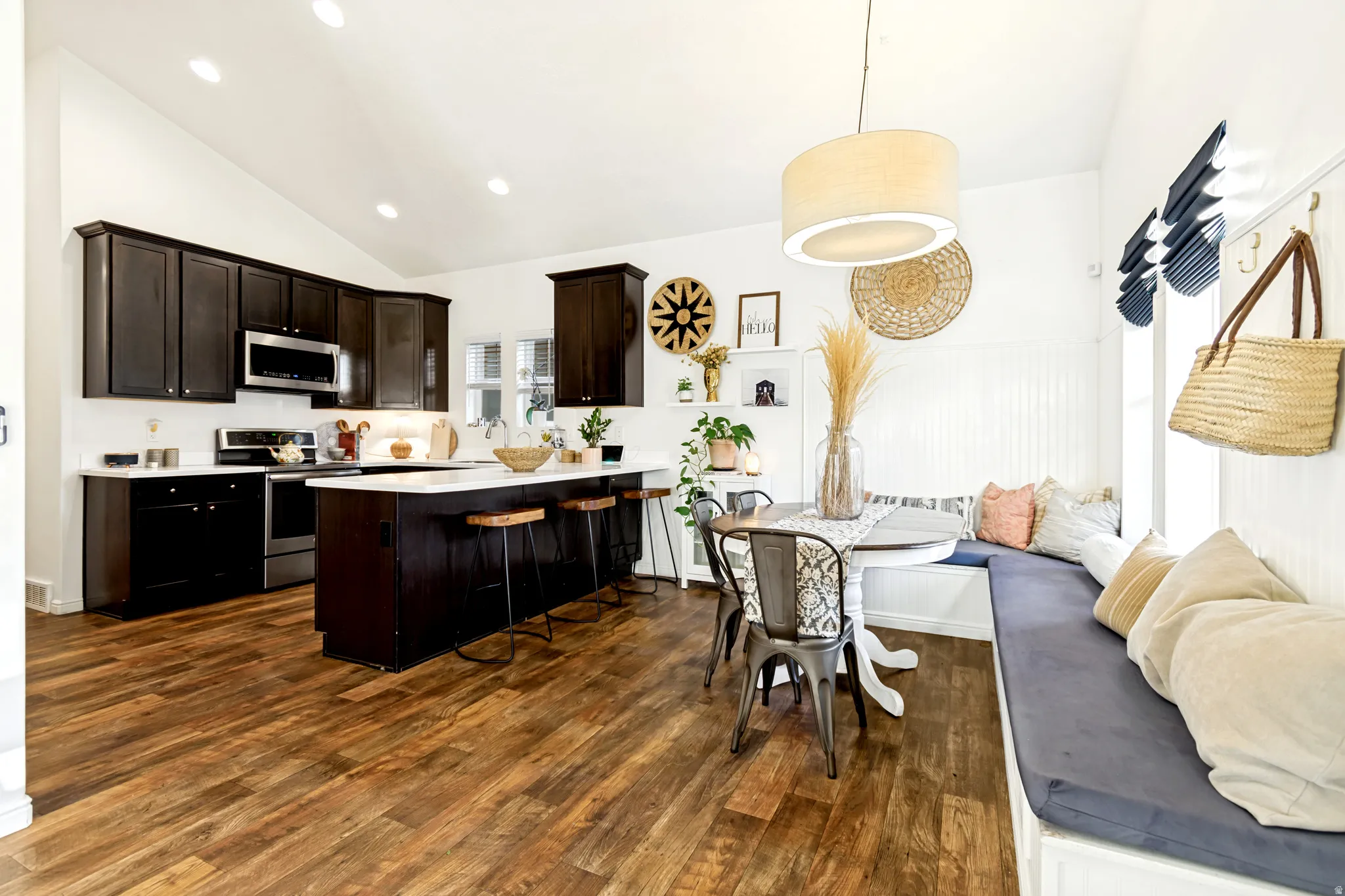 Kitchen with a peninsula, dark wood finish cabinets, lofted ceiling, stainless steel appliances, and a breakfast bar area