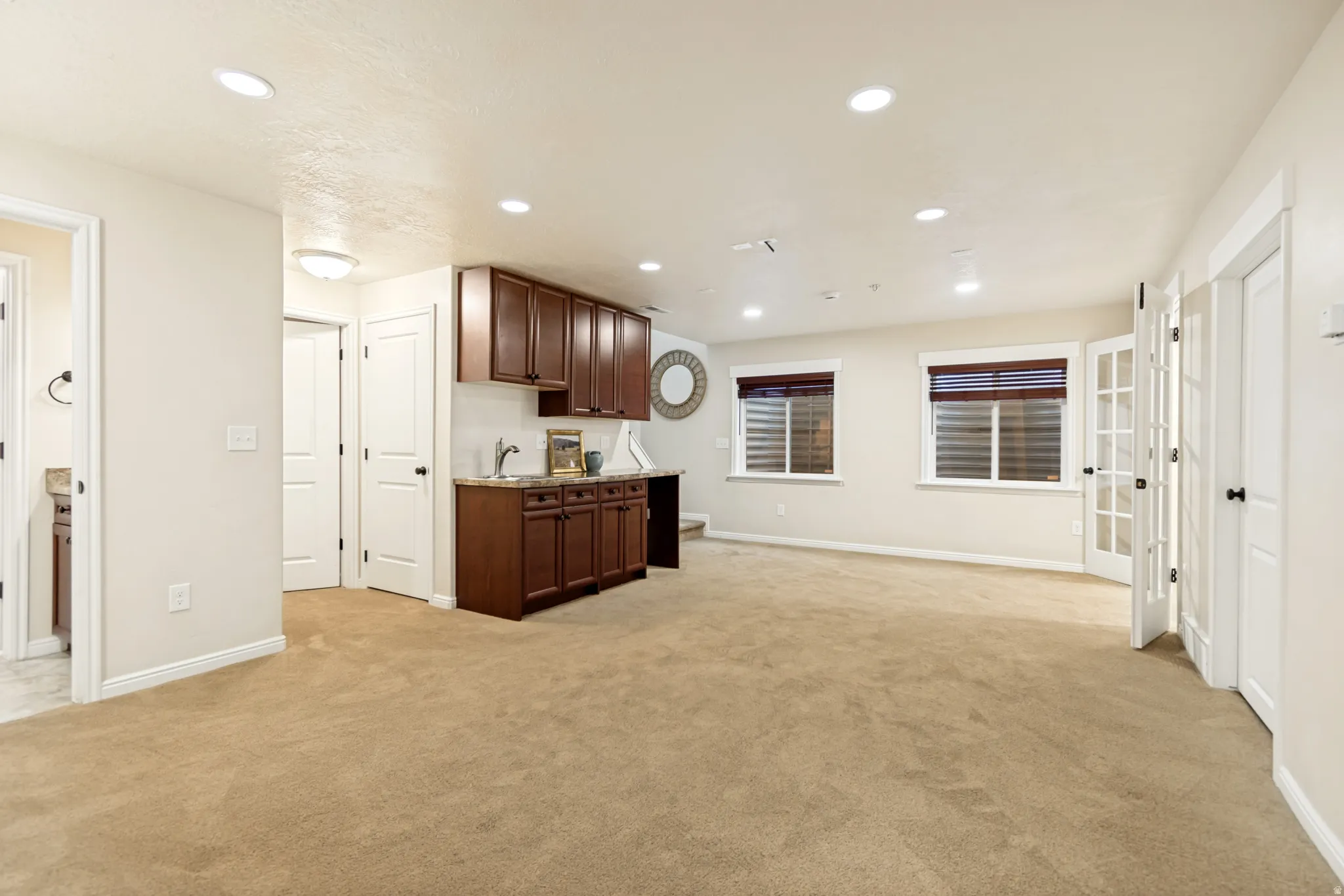 Kitchen featuring recessed lighting, light carpet, dark wood finish cabinetry, and light stone countertops