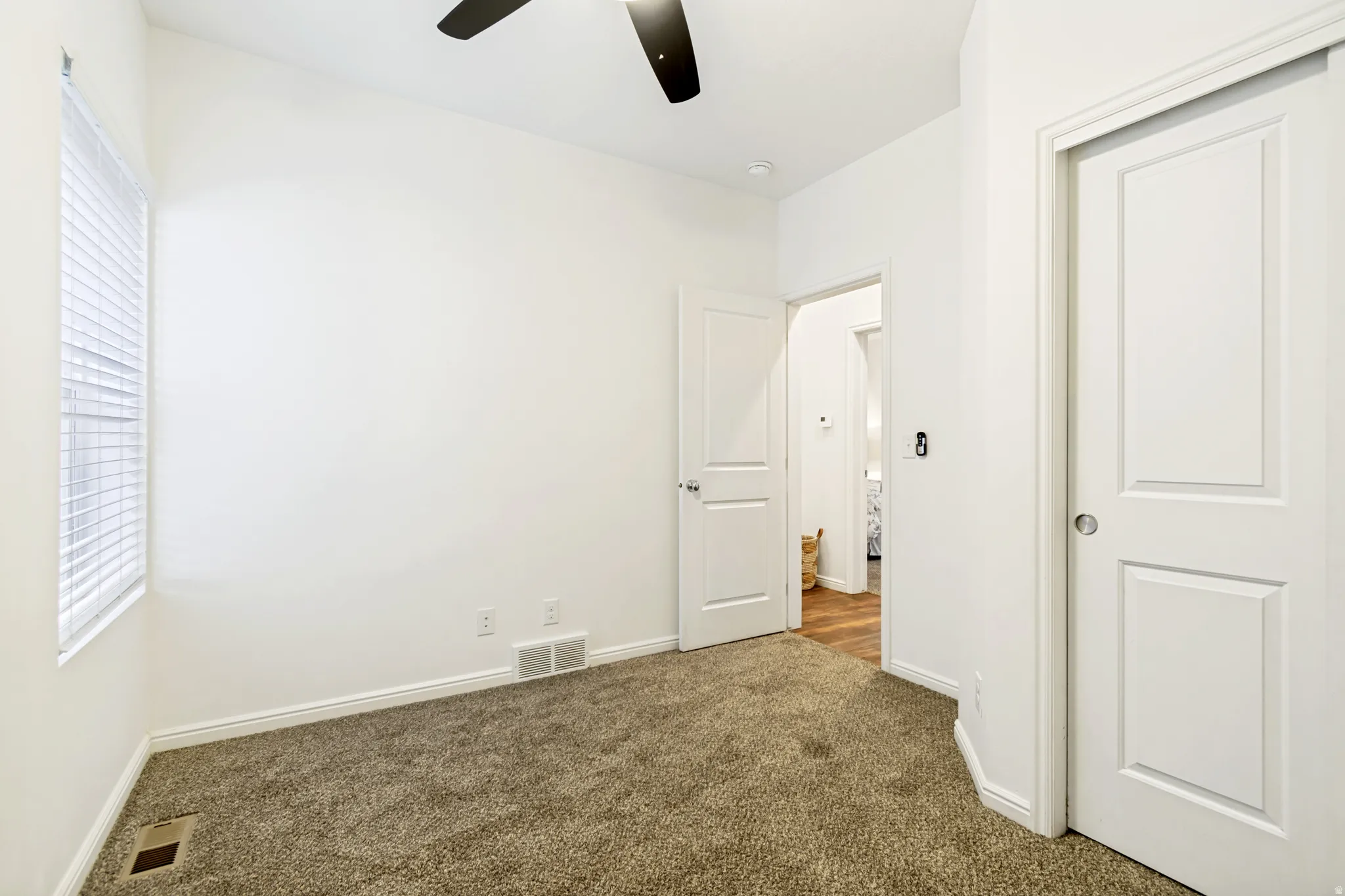 Unfurnished bedroom featuring dark carpet and ceiling fan