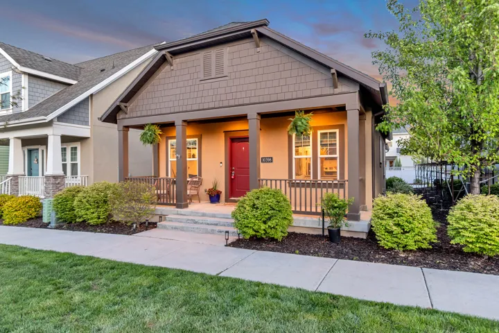 Craftsman-style home with a porch, stucco siding, a shingled roof, and a yard