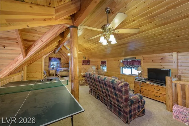 Living area featuring wood walls, light colored carpet, and a wooden ceiling with exposed beams