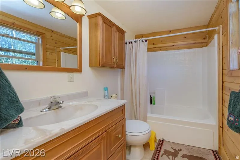 Full bathroom with vanity, shower / bath combination with curtain, and wood walls
