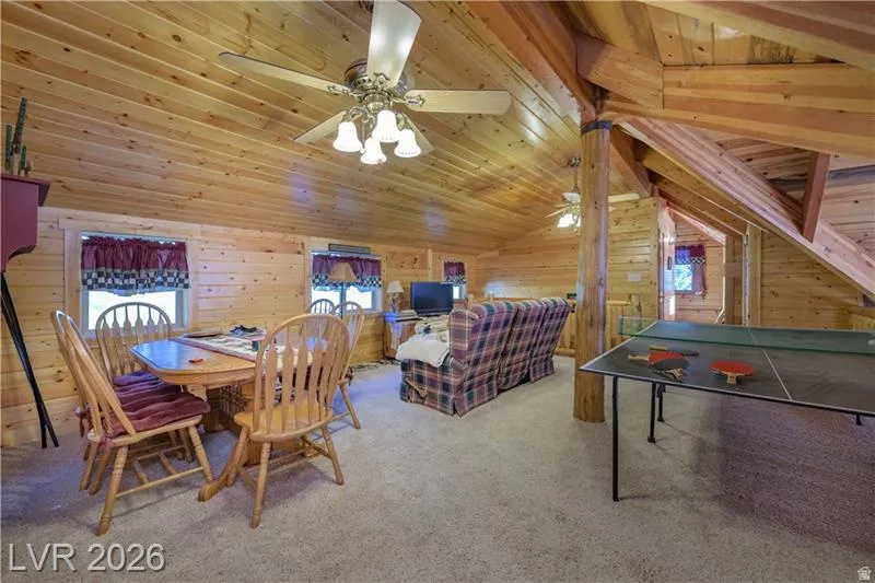 Dining room featuring wood walls, light colored carpet, and a vaulted wooden ceiling
