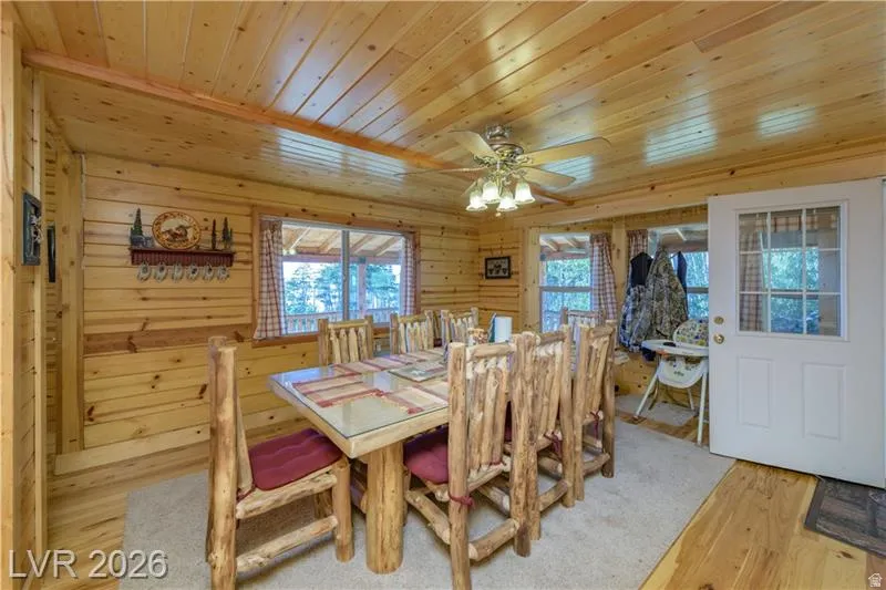 Dining space with wooden ceiling, ceiling fan, light wood-style flooring, and wood walls