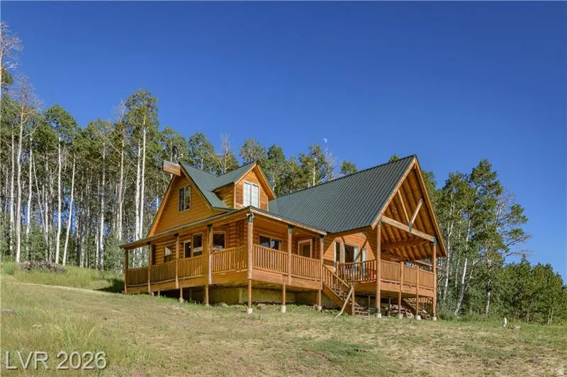 Rear view of house with a porch, a metal roof, and view of wooded area