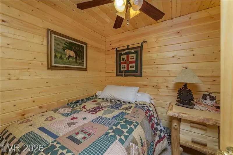 Bedroom featuring wooden walls and ceiling fan