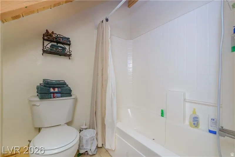 Bathroom featuring toilet and shower / bath combination with curtain