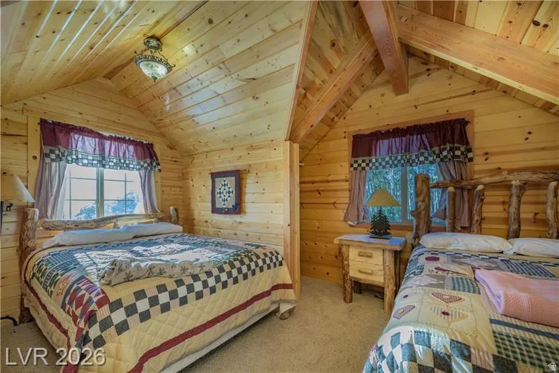 Carpeted bedroom with wood walls and a wooden ceiling with exposed beams