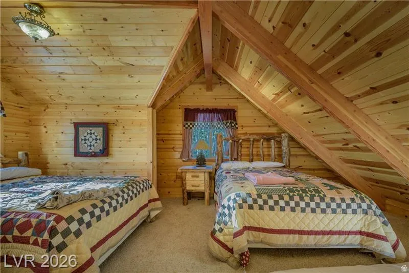 Carpeted bedroom with a wood ceiling with exposed beams and wood walls