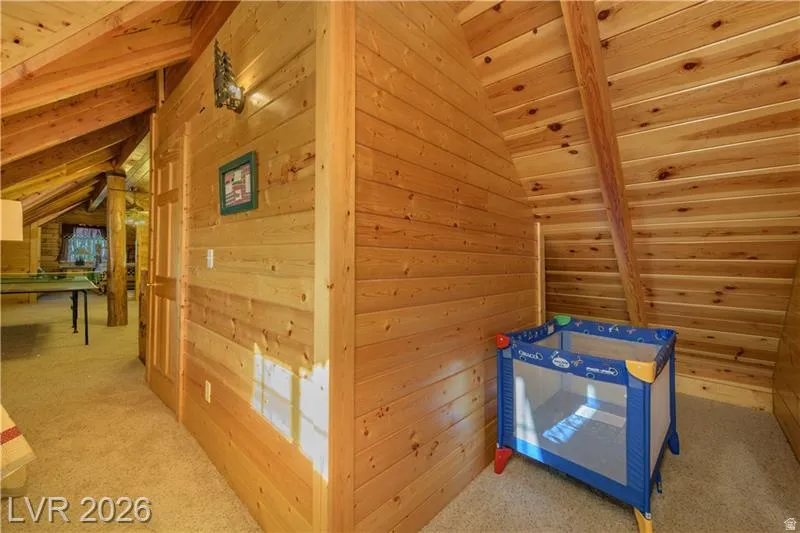 Corridor featuring lofted ceiling with beams, carpet flooring, wood ceiling, and wood walls