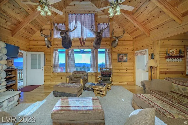 Living area with ceiling fan, wood finished floors, and a high wooden beamed ceiling