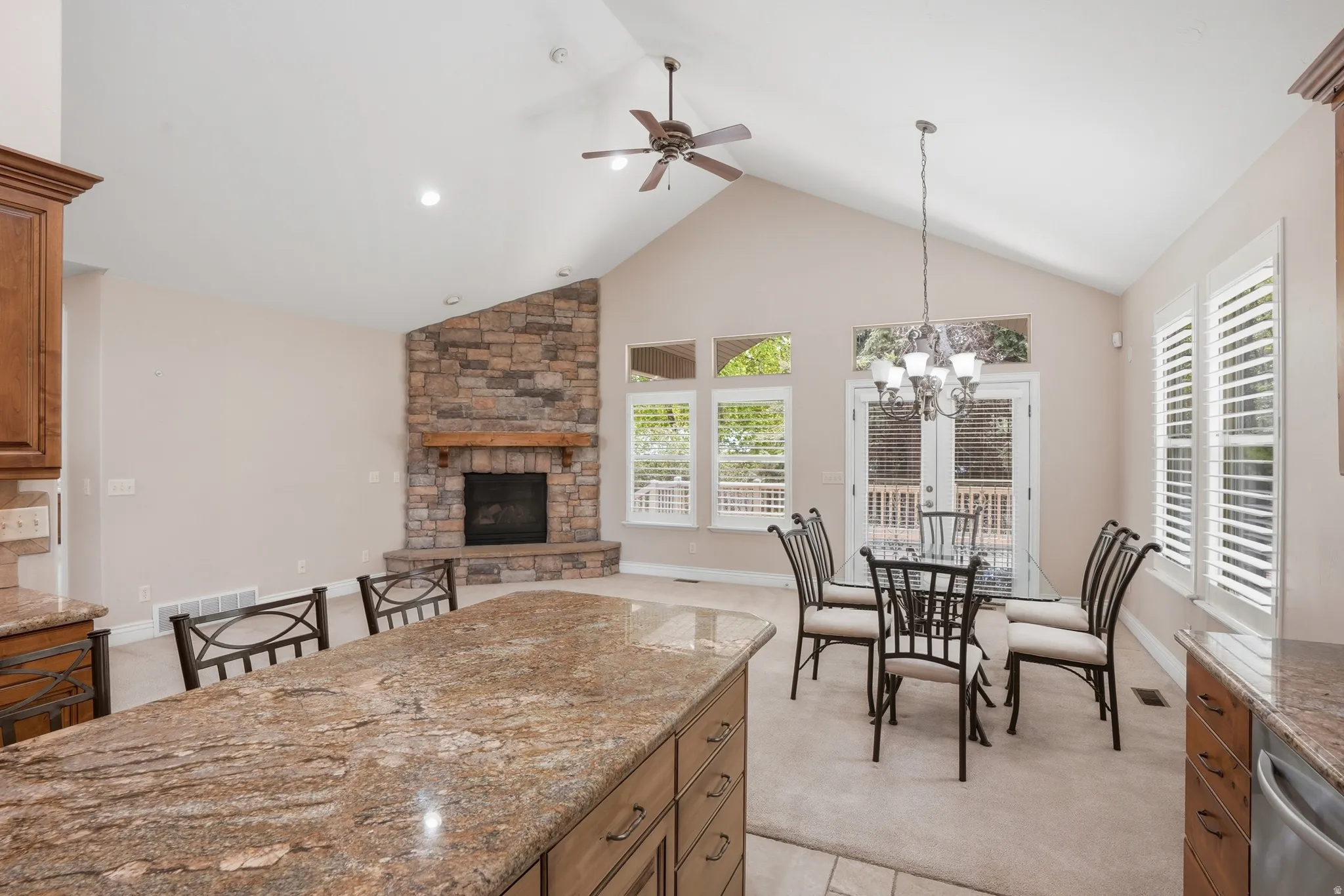 Kitchen with wood finish cabinets, granite counters, light carpet, ceiling fan, and open floor plan