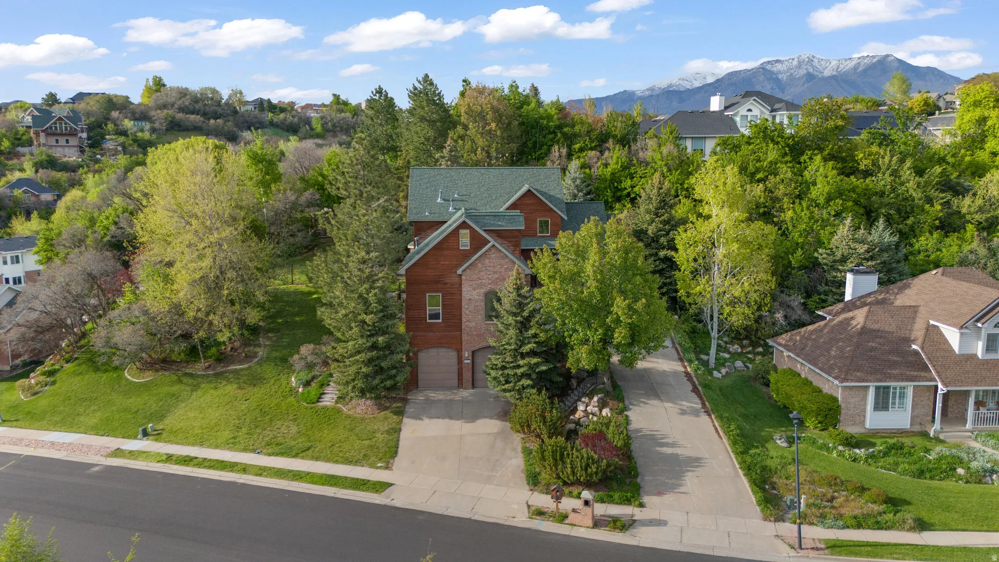 Aerial perspective of suburban area featuring a mountainous background and a tree filled landscape