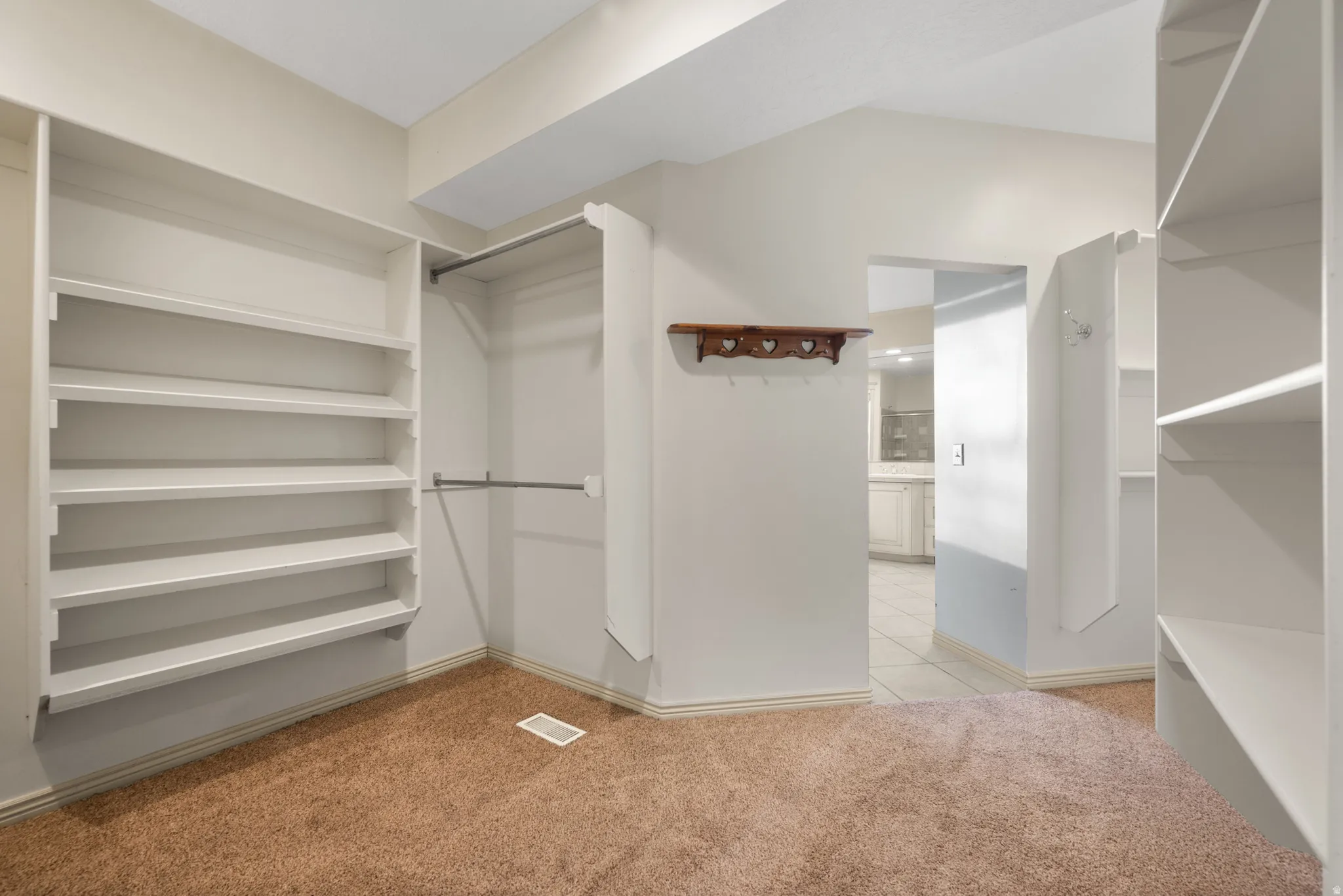 Primary Bedroom Walk in closet with light colored carpet
