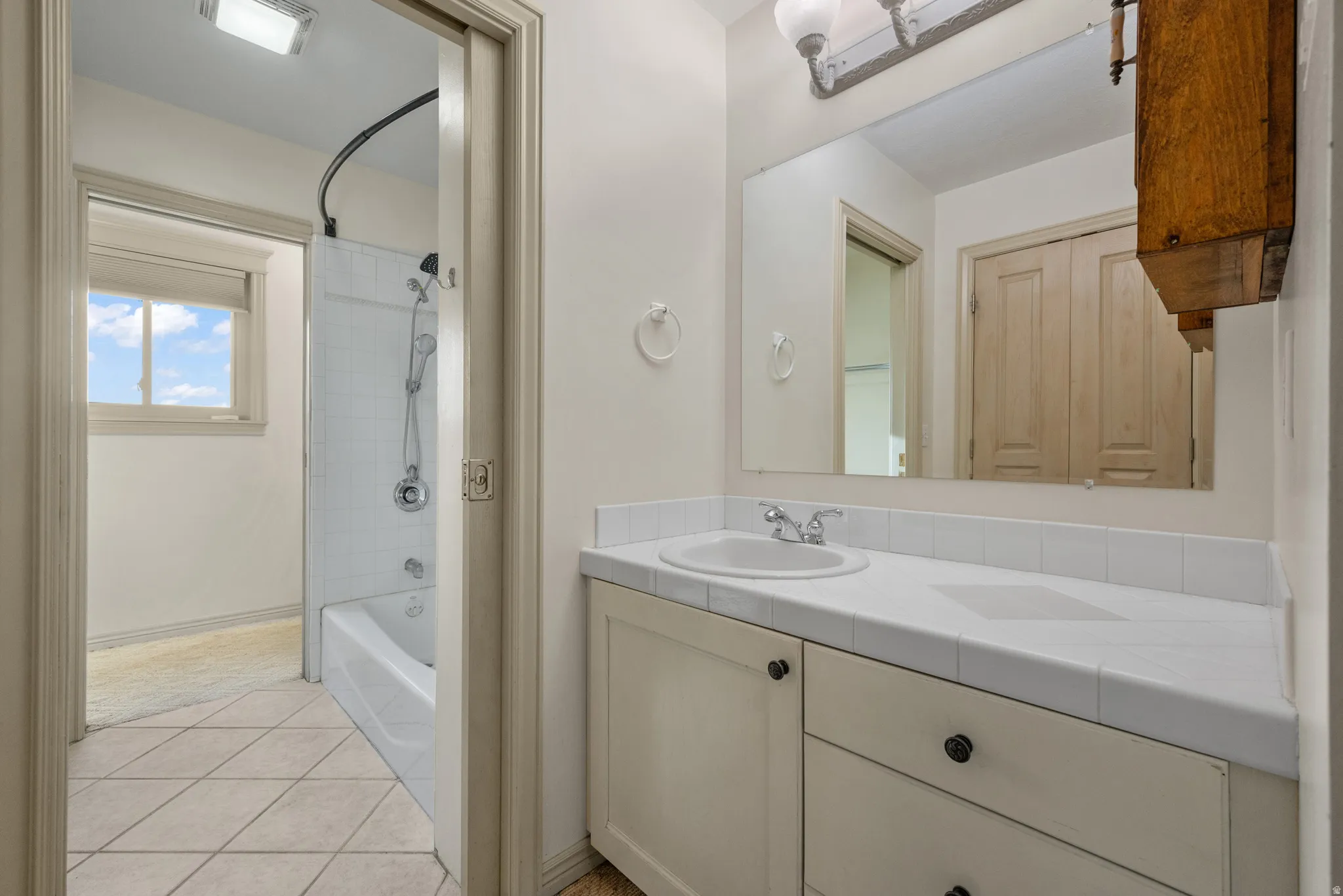Bathroom featuring vanity, light tile patterned flooring, and bathing tub / shower combination