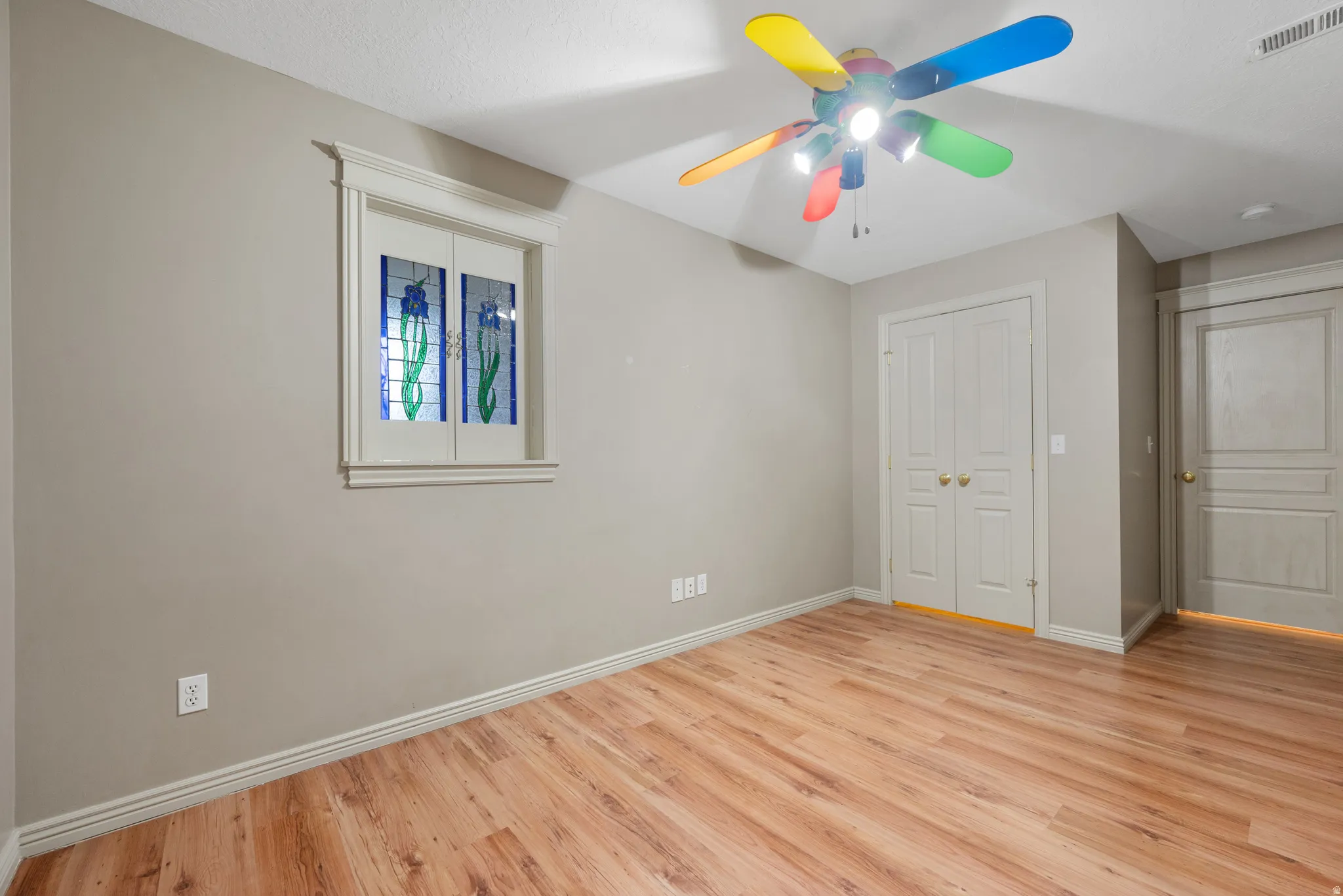 Unfurnished bedroom with light wood-style floors, a ceiling fan, and a closet