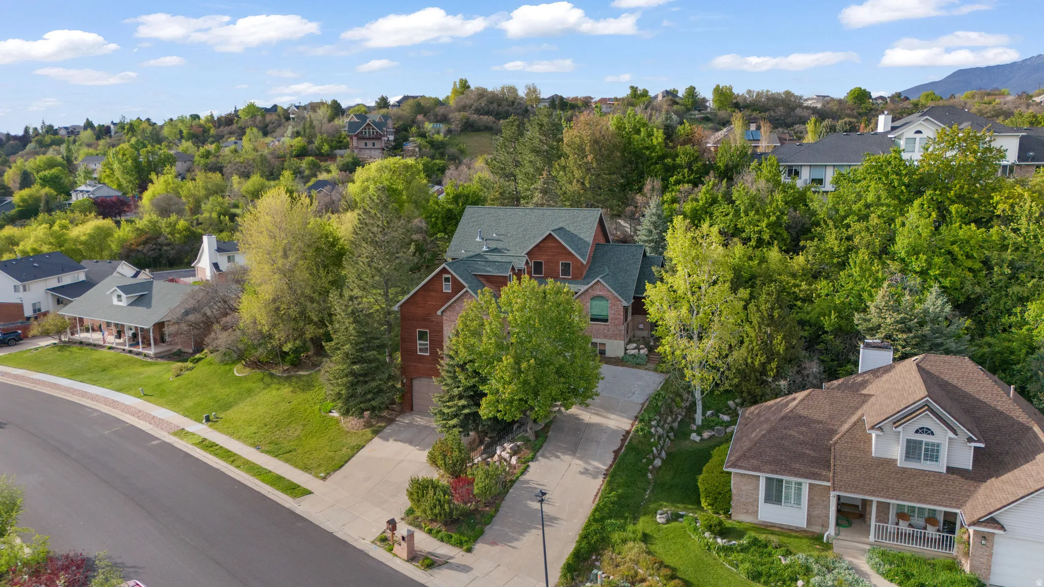 Aerial view of residential area with a tree filled landscape and a mountainous background