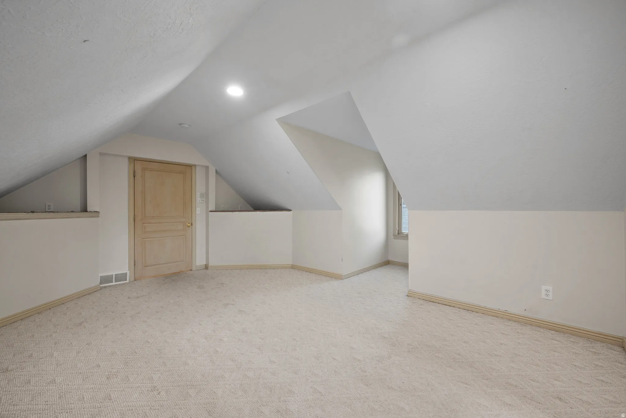 Additional living space featuring light carpet and lofted ceiling