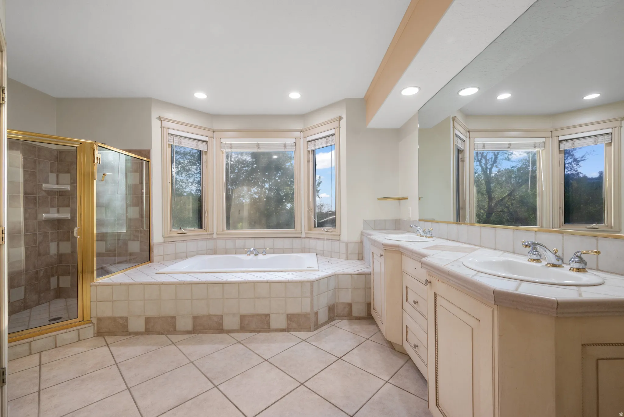 Primary Bathroom with a stall shower, double vanity, a bath, healthy amount of natural light, and recessed lighting