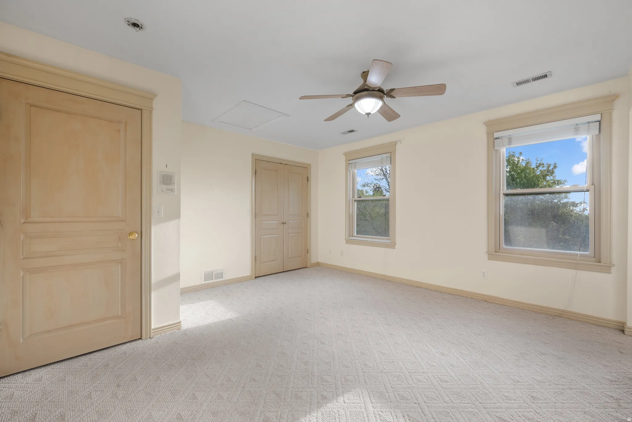 Unfurnished bedroom with light carpet, ceiling fan, and a closet