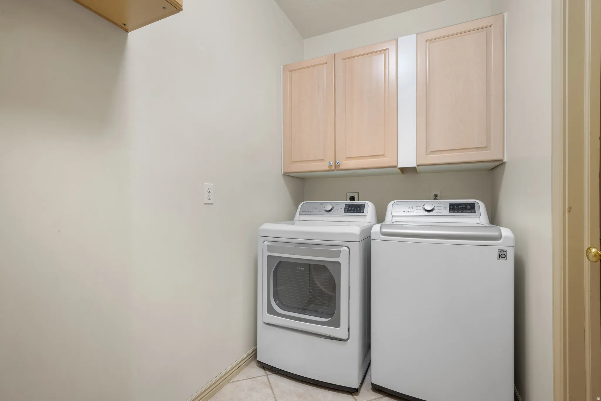 Laundry room with washer and clothes dryer, cabinet space, and light tile patterned flooring