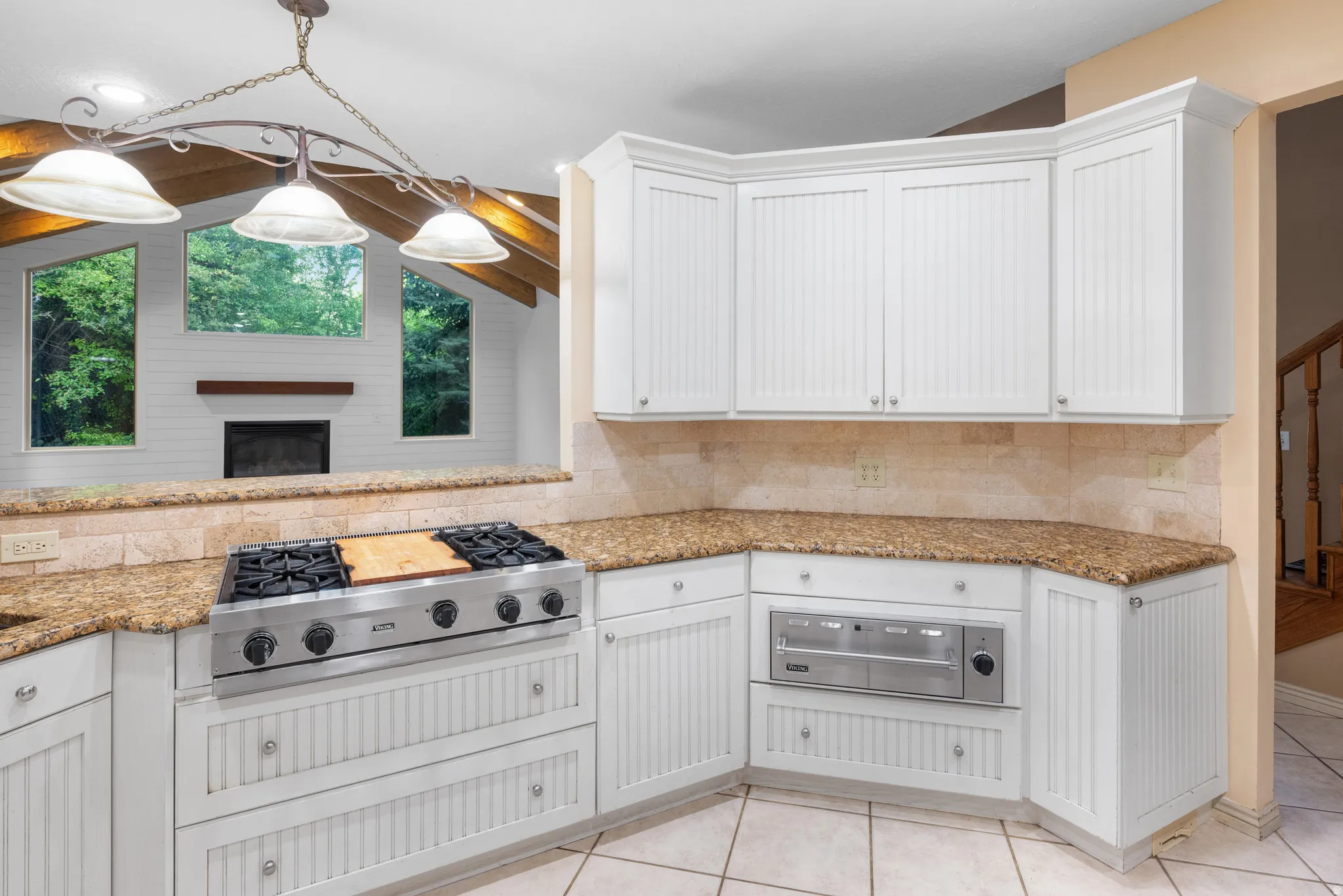 Kitchen featuring light stone countertops, stainless steel gas cooktop, white cabinets, and pendant lighting