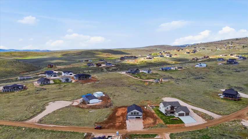 Aerial view of property and surrounding area featuring nearby suburban area and a mountainous background