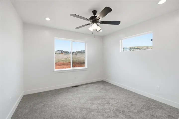 Spare room featuring light carpet, healthy amount of natural light, ceiling fan, and recessed lighting
