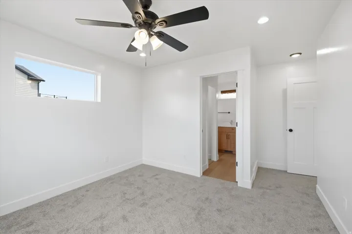 Unfurnished bedroom with light colored carpet, ensuite bath, a ceiling fan, and recessed lighting