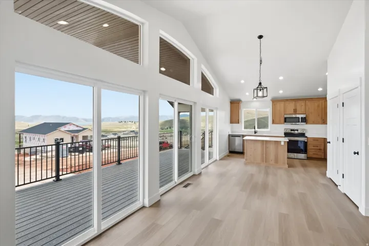 Kitchen with light countertops, stainless steel appliances, light wood-style flooring, vaulted ceiling, and a kitchen island