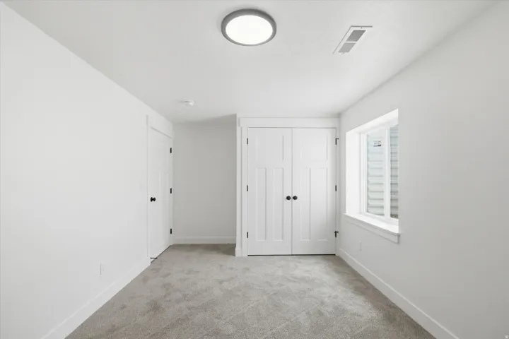 Unfurnished bedroom featuring a closet and light carpet
