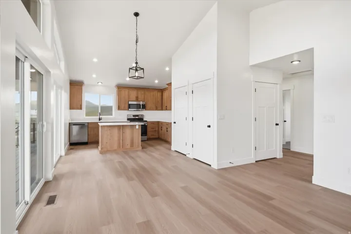 Kitchen with light countertops, open floor plan, a high ceiling, a kitchen island, and stainless steel appliances