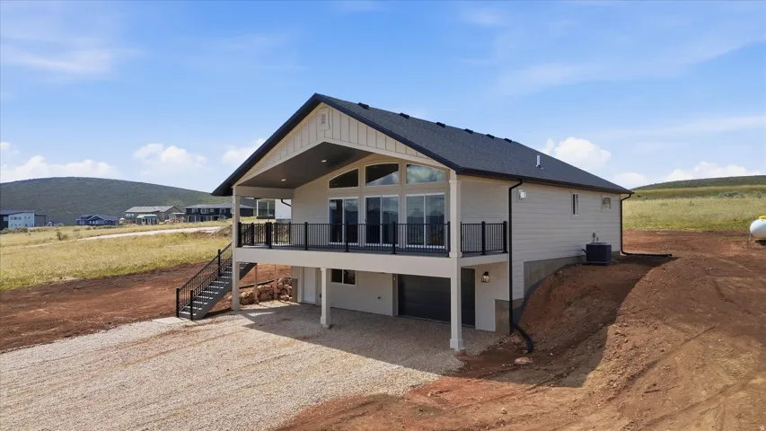 View of front facade featuring a garage, gravel driveway, roof with shingles, a patio, and a mountain view