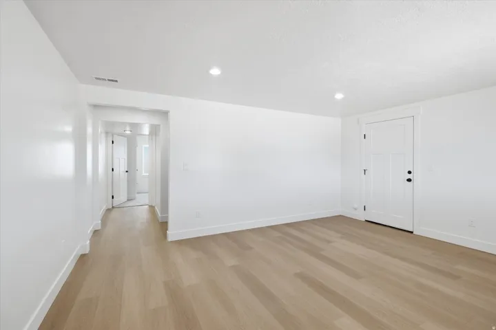 Empty room featuring light wood-type flooring and recessed lighting