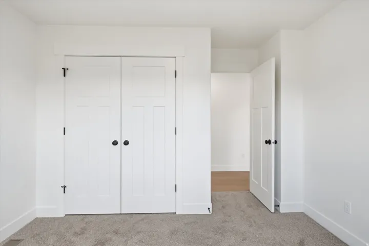Unfurnished bedroom featuring light carpet and a closet