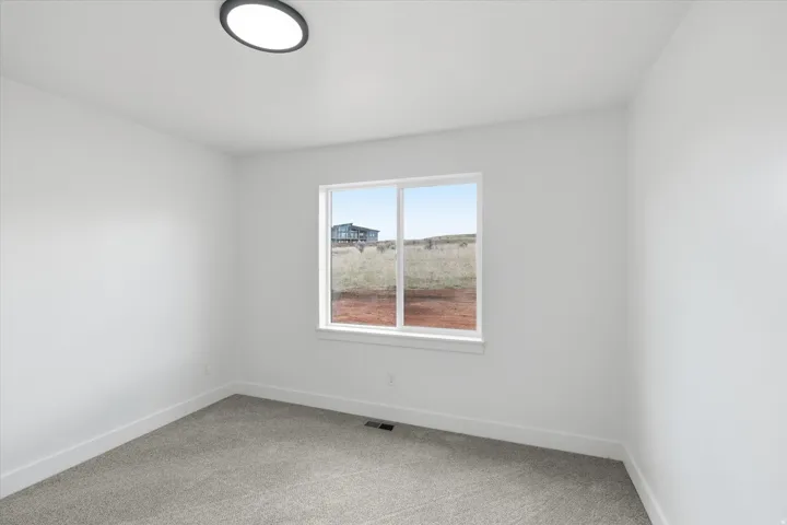 Spare room with baseboards and light colored carpet