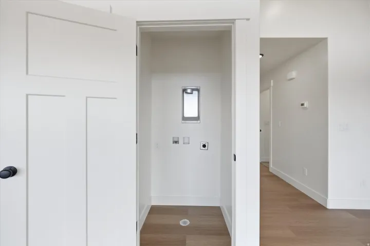 Laundry area with light wood-style floors, electric dryer hookup, and washer hookup