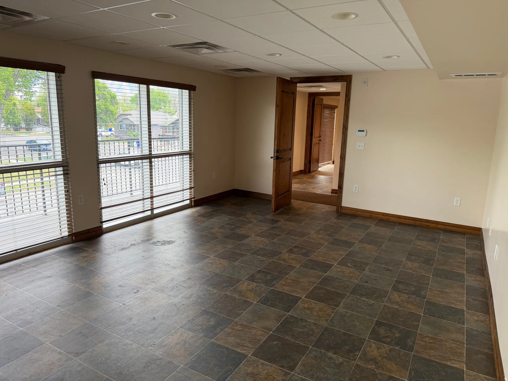 Empty room featuring a paneled ceiling and dark stone finish flooring