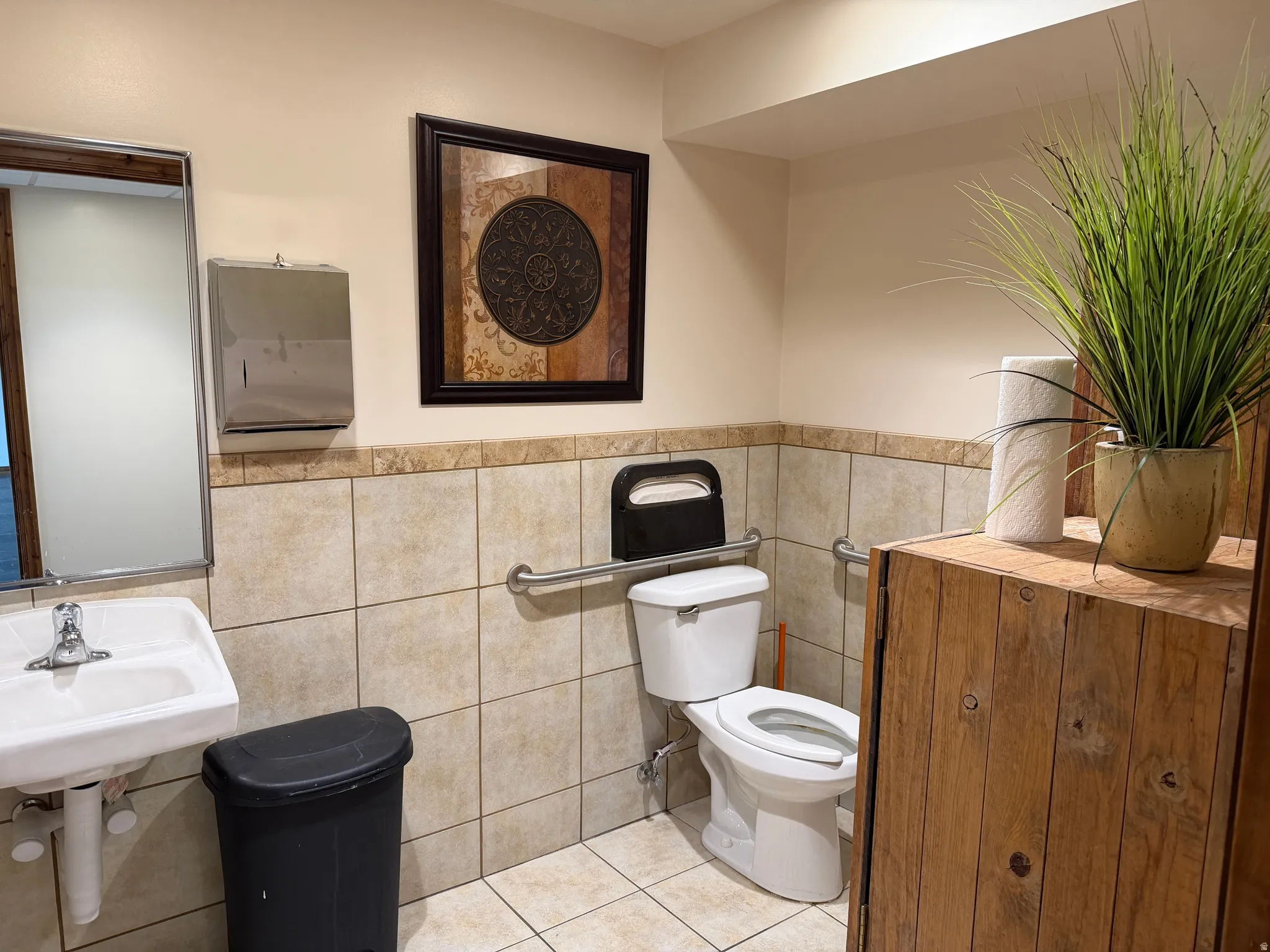 Half bath featuring light tile patterned flooring, tile walls, and wainscoting