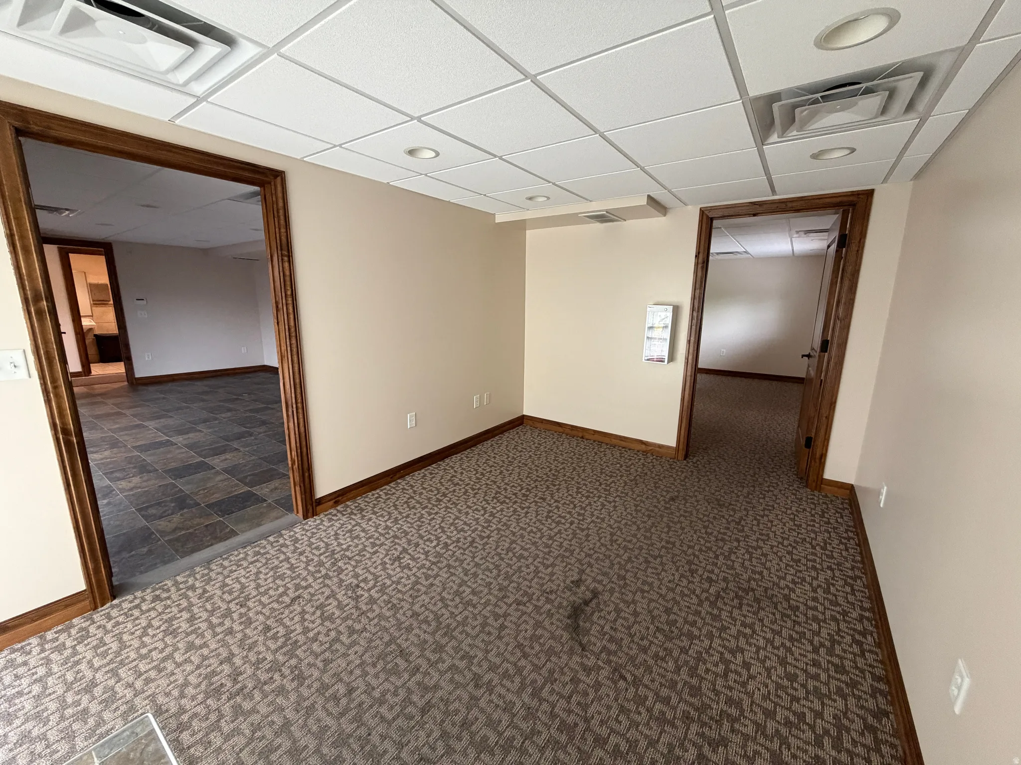 Unfurnished room featuring dark carpet and a paneled ceiling