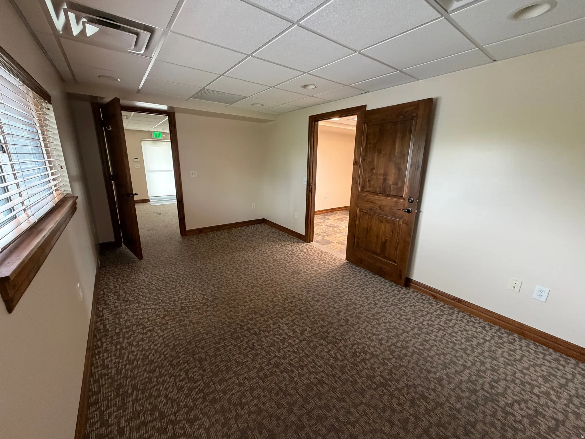 Empty room with a paneled ceiling and carpet floors