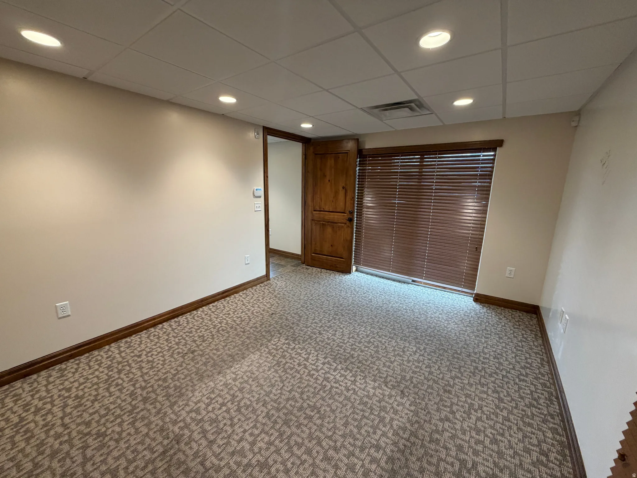 Unfurnished room with light colored carpet, recessed lighting, and a drop ceiling