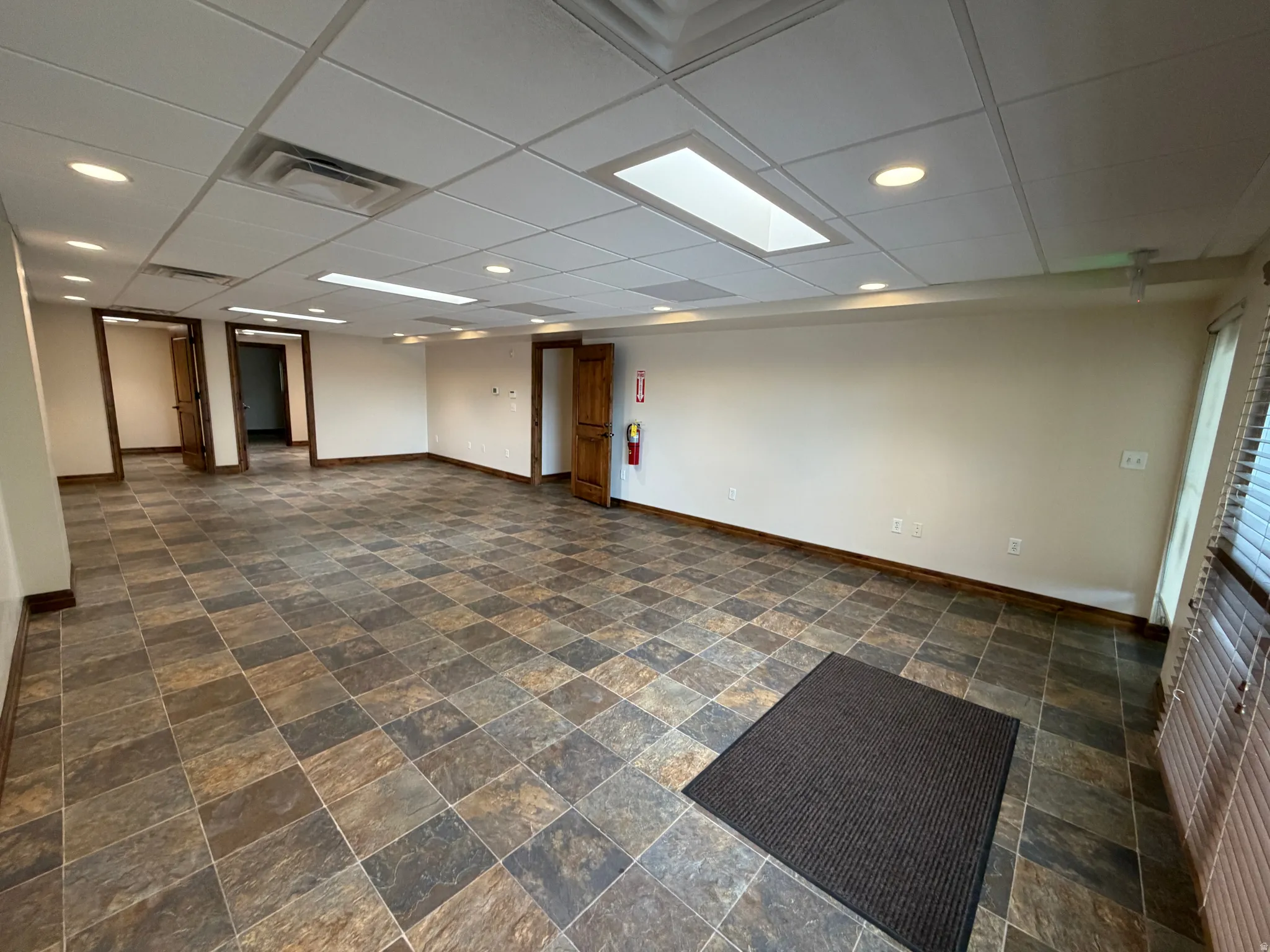 Empty room with dark stone finish flooring, a drop ceiling, and recessed lighting